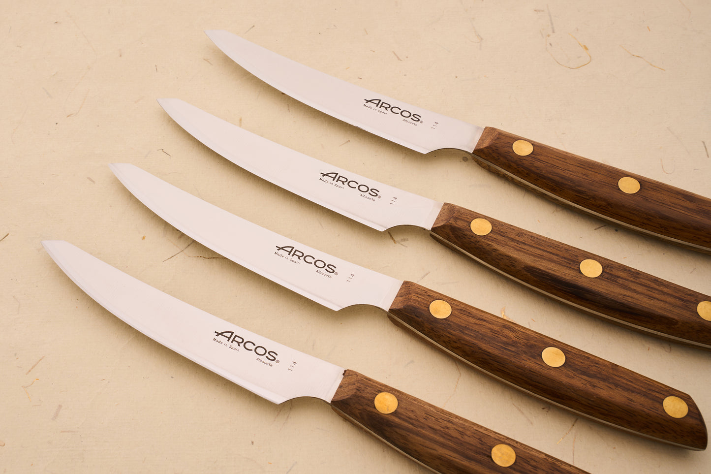 Arcos Nordika 4pc Steak Knife Set, featuring stainless steel blades with wood handles, expertly crafted in Spain, ideal for precise, clean cuts.