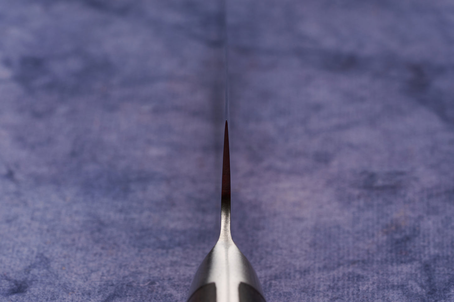 Hazaki Classic Black Petty 90mm knife edge on textured cloth, showcasing its thin, sharp AUS10 steel blade and just-visible blackwood handle, embodying a fusion of Japanese craftsmanship and Canadian artistry.