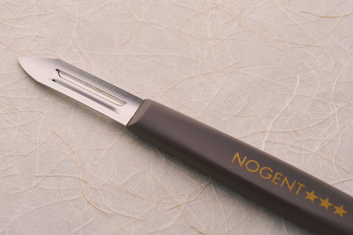 Nogent Double Edge Peeler with a stainless-steel blade and brown handle, designed for dual directional peeling, showcasing craftsmanship and durability.