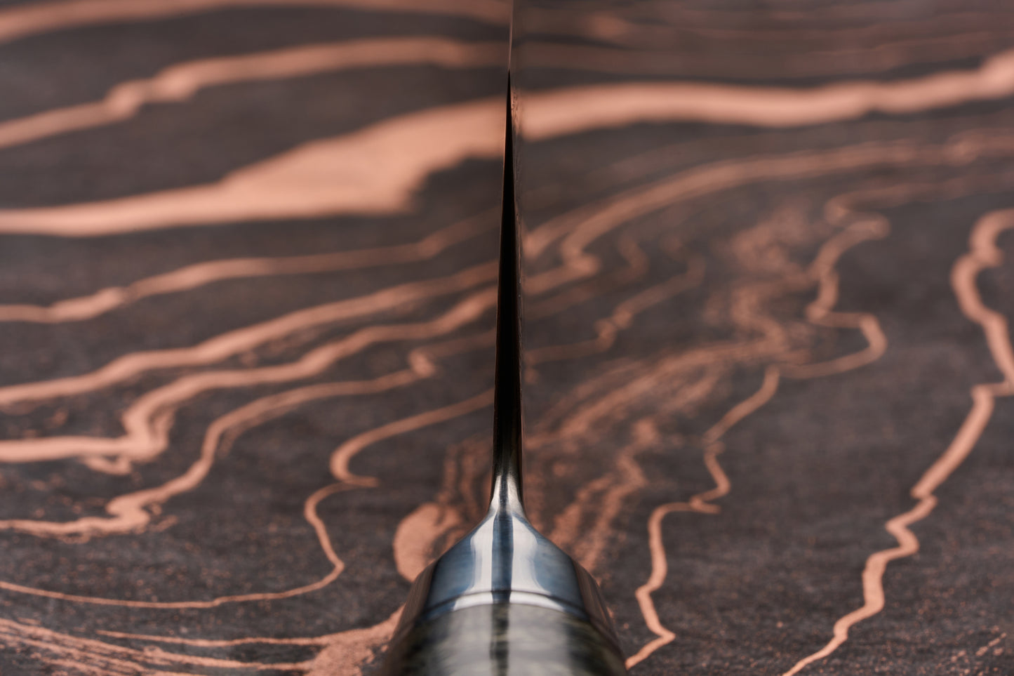 Close-up of Ryusen Oukokuryu Gyuto 240mm, showcasing its thin, sharp blade edge standing upright on a dark wooden surface. The knife embodies traditional Japanese craftsmanship and modern design elegance.