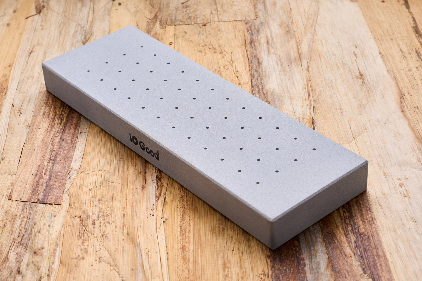 10 Good Coarse 300 Grit Stone with perforated surface, ideal for beginners in knife sharpening, resting on a wooden surface.