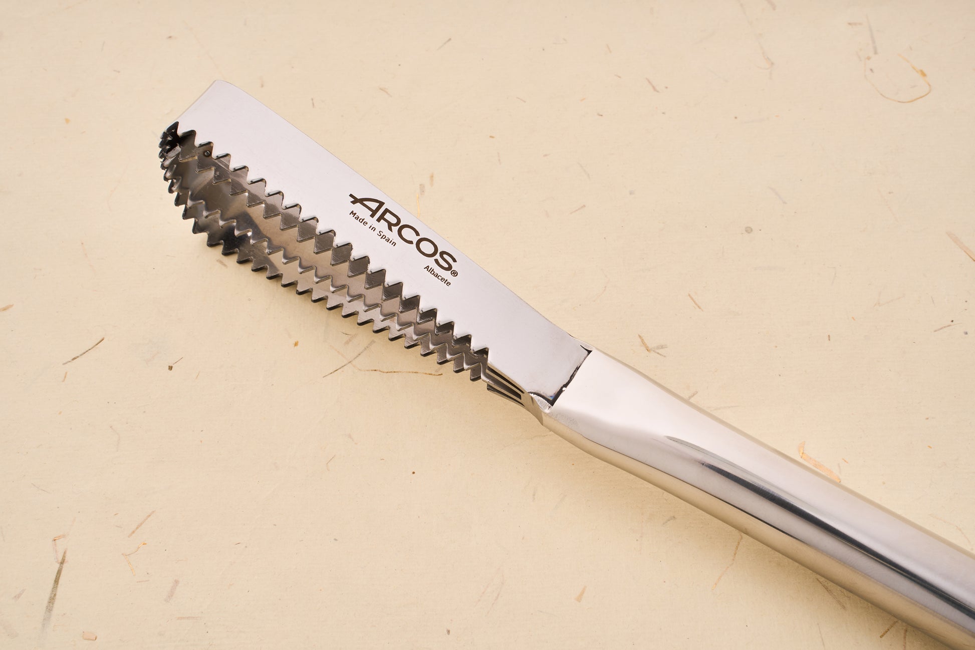 Close-up of Arcos Scaling Knife, featuring stainless-steel tongs with serrated tips, stamped with ARCOS, Made in Spain (Albacete).