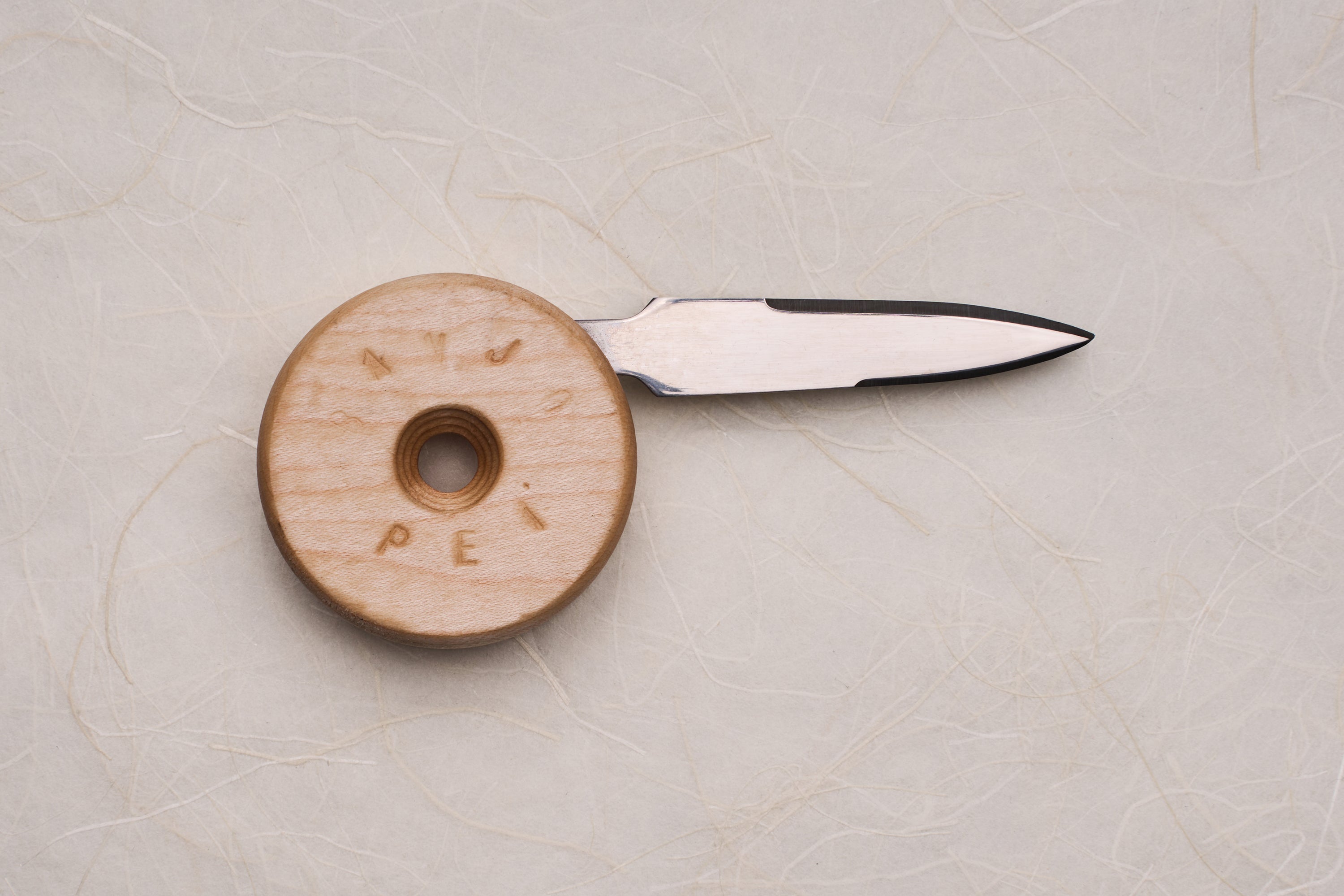 Banjo Oyster Knife with a double-edged blade tucks into a circular wooden handle, designed for ergonomic shucking. Inspired by skateboard wheels, crafted in Canada, perfect for oyster enthusiasts.
