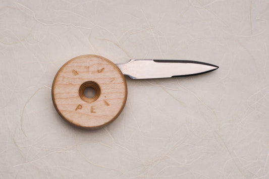 Banjo Oyster Knife with a double-edged blade tucks into a circular wooden handle, designed for ergonomic shucking. Inspired by skateboard wheels, crafted in Canada, perfect for oyster enthusiasts.