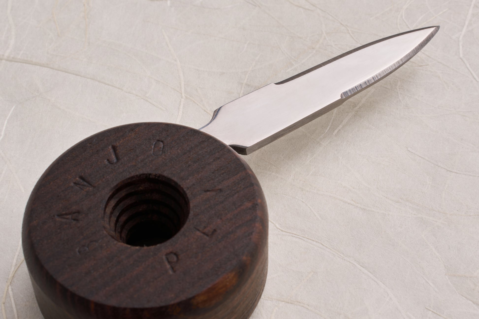 Banjo Oyster Knife blade close-up on a wooden holder with threaded socket, showcasing its precision design for safer shucking, reflecting Knifewear's dedication to quality handcrafted kitchen tools.