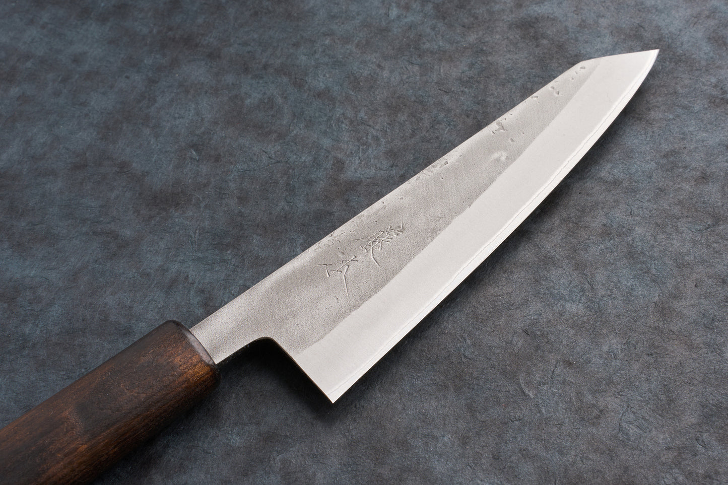 Fujimoto Nashiji Honesuki 150mm, a Japanese-style knife with a polished steel blade featuring hammer-marks and kanji engravings, paired with a classic dark wooden wa handle, perfect for precise butchery.
