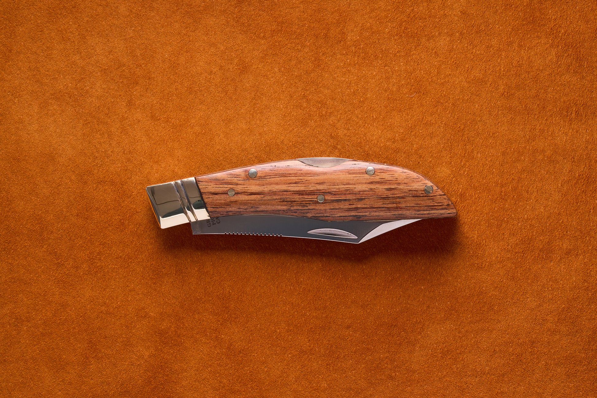 Grohmann Mini Russell Lockblade with Rosewood Handle, 4 Clip Point, on suede surface, showcasing its compact design and stainless steel blade for versatile use.