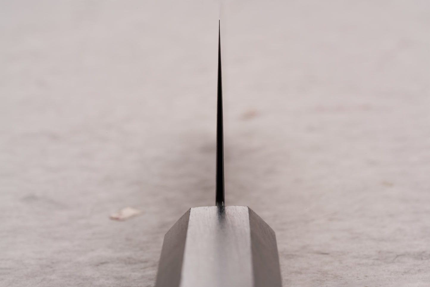 Hatsukokoro Ryuhyo SG2 Kurozome Damascus Bunka 180mm knife emerges from a wooden block, showcasing its ultra-thin, black blade, epitomizing precision and artistry in Japanese kitchen craftsmanship.