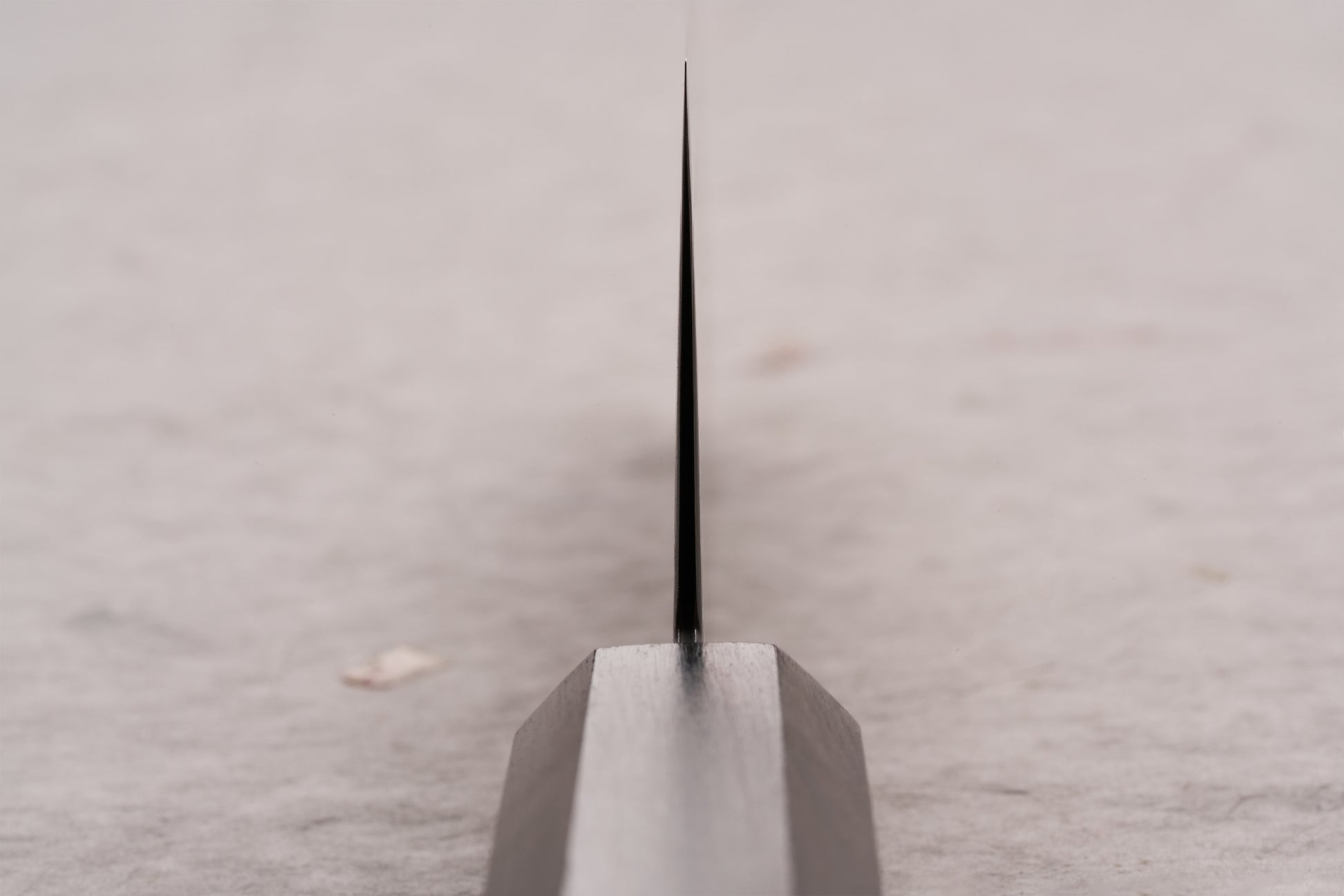Hatsukokoro Ryuhyo SG2 Kurozome Damascus Bunka 180mm knife emerges from a wooden block, showcasing its ultra-thin, black blade, epitomizing precision and artistry in Japanese kitchen craftsmanship.