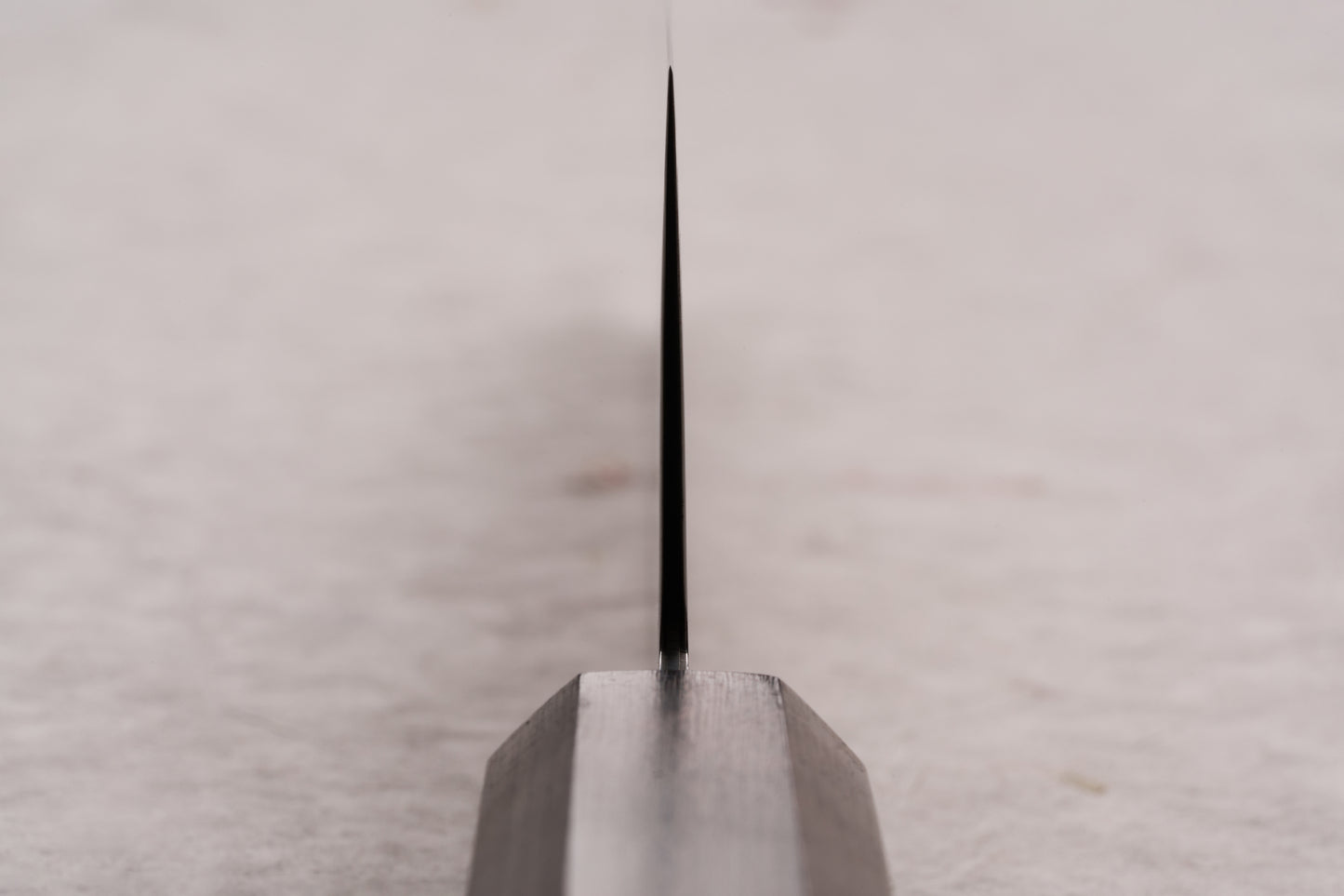 Hatsukokoro Ryuhyo SG2 Kurozome Damascus Kiritsuke Gyuto 210mm knife blade, viewed edge-on, showcasing its precise, whisper-thin grind, crafted by skilled artisans in Seki for exceptional sharpness and performance.