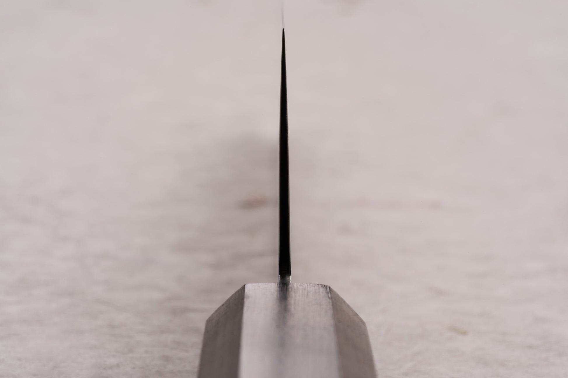 Hatsukokoro Ryuhyo SG2 Kurozome Damascus Kiritsuke Gyuto 210mm knife blade, viewed edge-on, showcasing its precise, whisper-thin grind, crafted by skilled artisans in Seki for exceptional sharpness and performance.