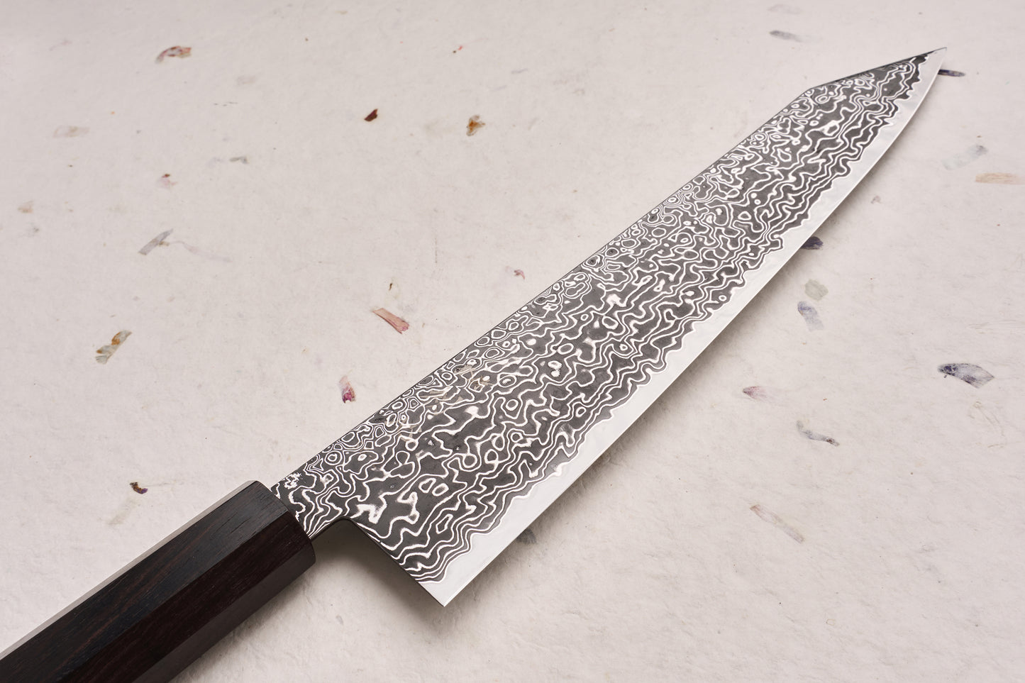 Hatsukokoro Ryuhyo SG2 Kurozome Damascus Kiritsuke Gyuto 240mm, featuring a striking Damascus steel blade with a swirling pattern and a sleek dark wood handle, exemplifies expert Japanese craftsmanship.