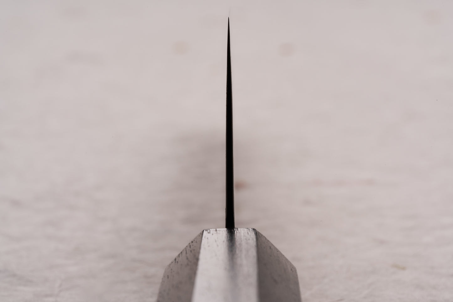 Hatsukokoro Ryuhyo SG2 Kurozome Damascus Kiritsuke Gyuto 240mm, viewed head-on, highlights its razor-sharp, V-shaped blade edge, showcasing its precision craftsmanship and whisper-thin grind.