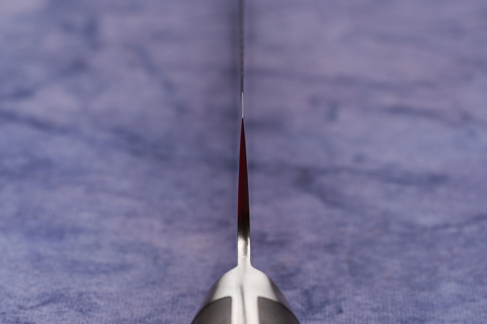 Hazaki Classic Black Bread Knife 240mm, expertly forged in Seki, Japan, features a razor-sharp, serrated blade edge-on view, with a sleek handle partially visible, set against a cloth background.