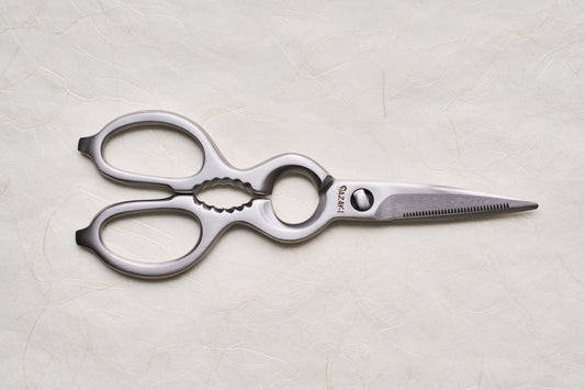 Hazaki Stainless Kitchen Shears with ergonomic handles and a serrated blade, featuring a bottle opener and nutcracker, displayed on a textured surface. Ideal for versatile kitchen tasks and easy maintenance.