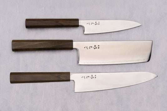 ICHIGO Nezu 3 Piece Knife Set displayed: utility, nakiri, and chef’s knives; polished blades with dark octagonal handles, showcasing Japanese craftsmanship and elegance.