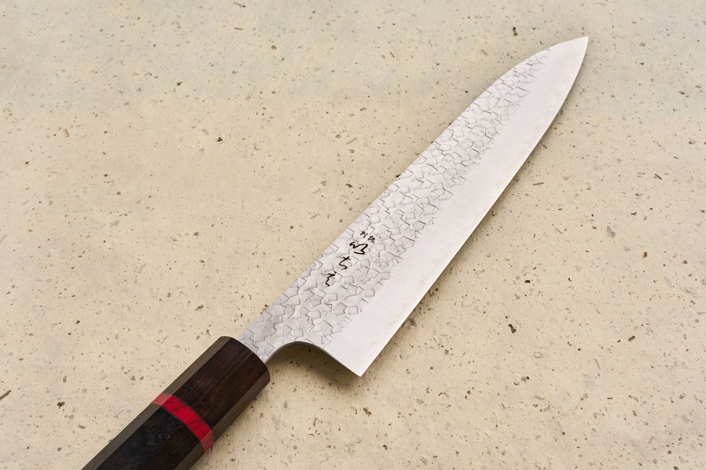 ICHIE x Shibata Knives SG2 Tsuchime Gyuto 210mm, featuring a hammered blade with Damascus patterning and an octagonal wooden handle, showcases Japanese craftsmanship ideal for versatile culinary use.