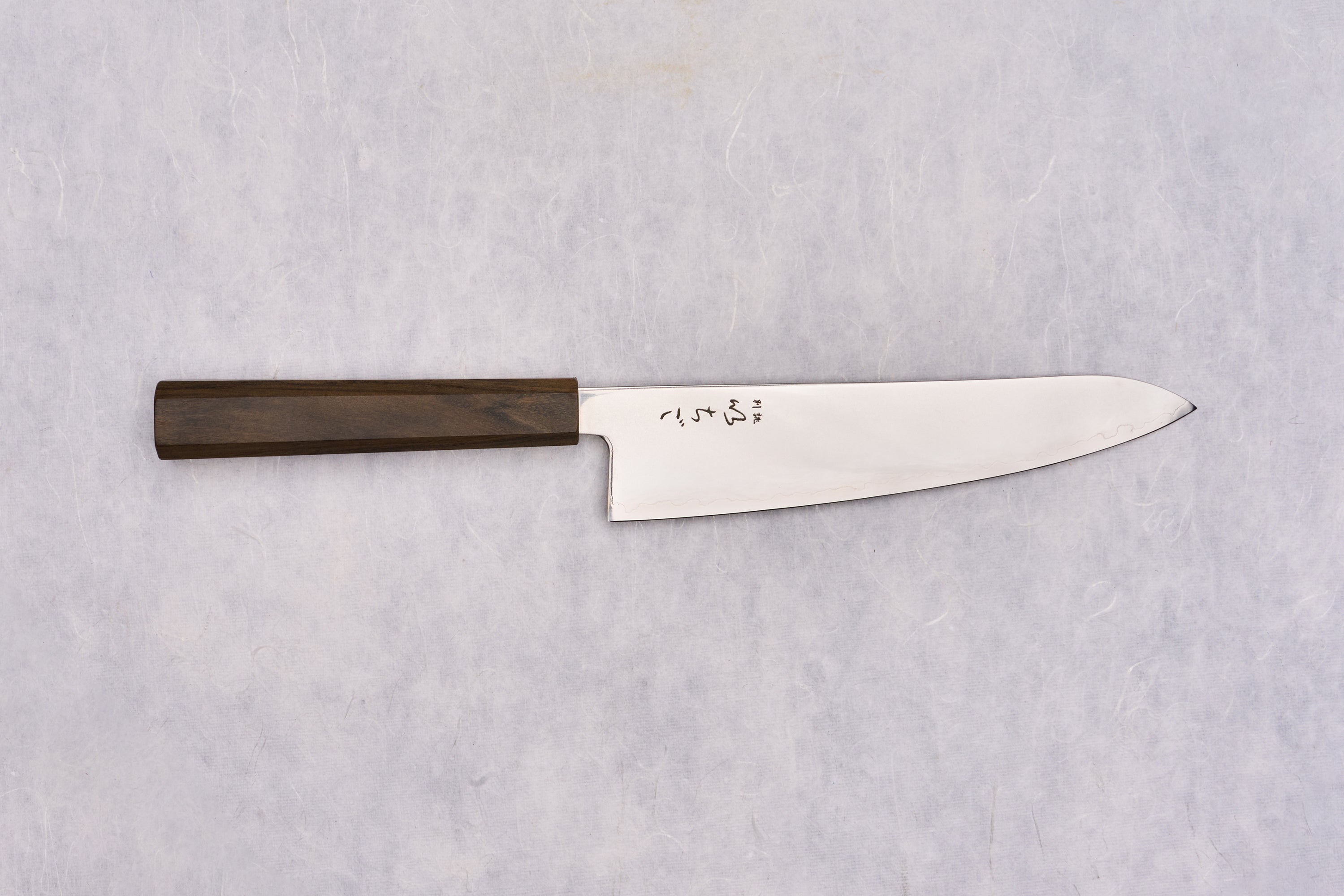 ICHIGO SLD Migaki Gyuto 195mm displayed flat, features a polished steel blade with engraved Japanese characters near the heel and an octagonal wooden handle, embodying Japanese craftsmanship.