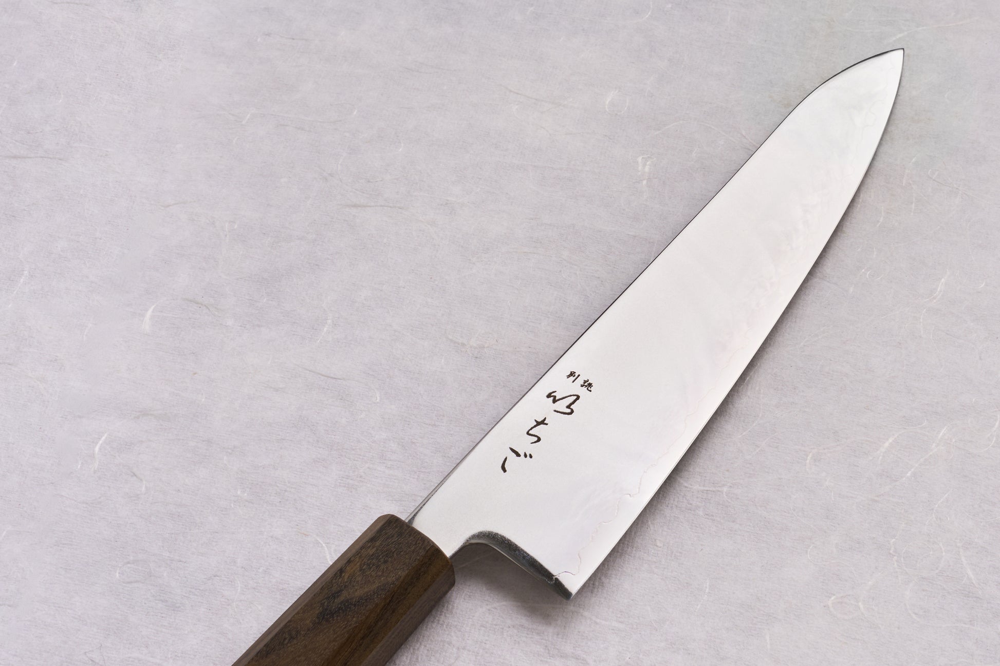 ICHIGO SLD Migaki Gyuto 195mm, showcasing a slender stainless blade with a subtle hamon and Japanese characters, features a dark octagonal wooden handle, epitomizing Japanese craftsmanship in kitchen knives.