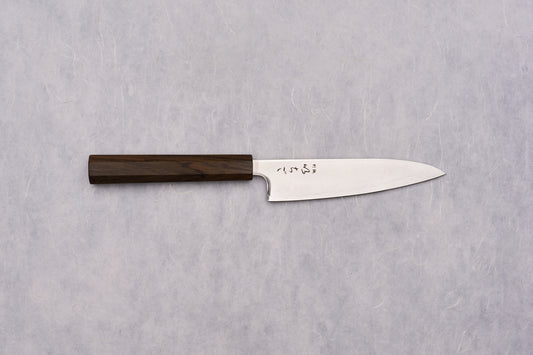 ICHIGO SLD Migaki Petty 130mm Japanese kitchen knife features a polished stainless-steel blade with a hamon line and kanji, paired with a dark octagonal wooden handle, ideal for precise kitchen tasks.