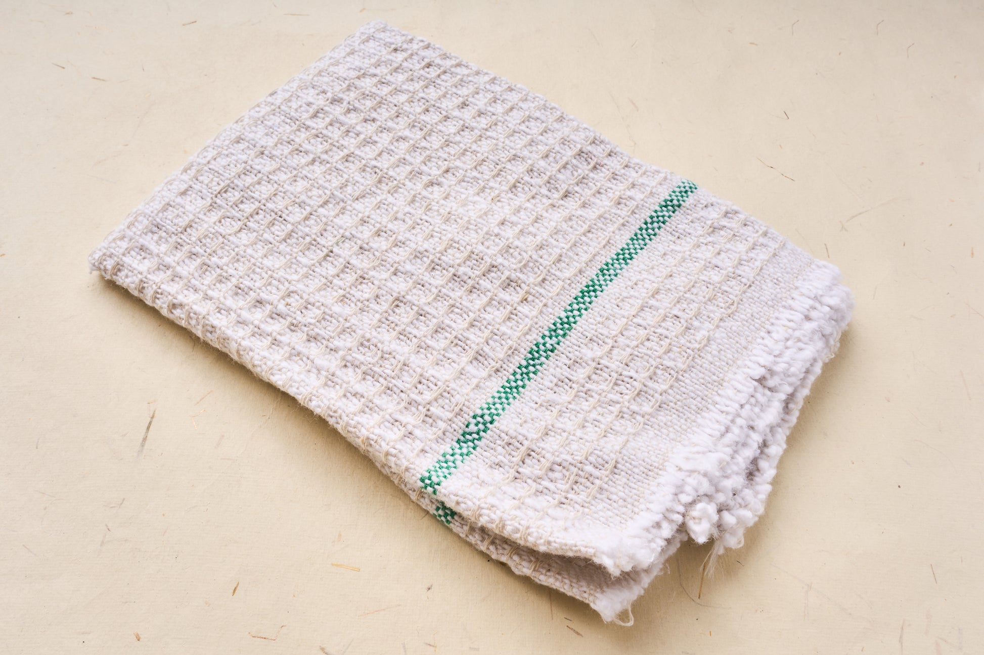 Iris Hantverk Cleaning Cloth made from 100% recycled woven cotton, featuring a waffle-weave design with a green stripe, folded neatly.