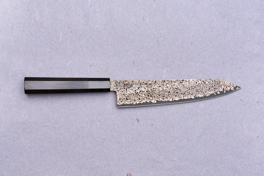 Kanjo SG2 Nickel Damascus Kiritsuke Gyuto 210mm: A Japanese chef's knife featuring a patterned Damascus blade and dark octagonal wooden handle, ideal for versatile kitchen tasks.