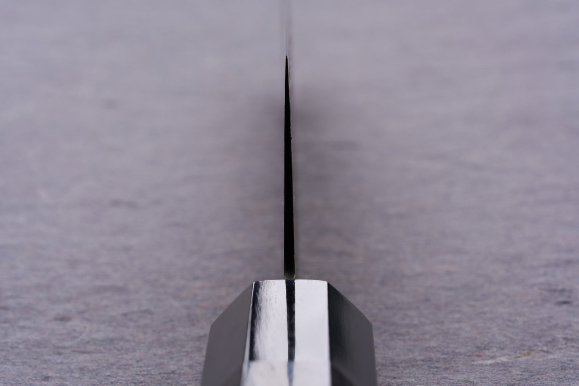 Extreme close-up of the Kanjo SG2 Nickel Damascus Kiritsuke Gyuto 210mm blade, showcasing its sharp edge and metal bolster, ideal for versatile culinary use.