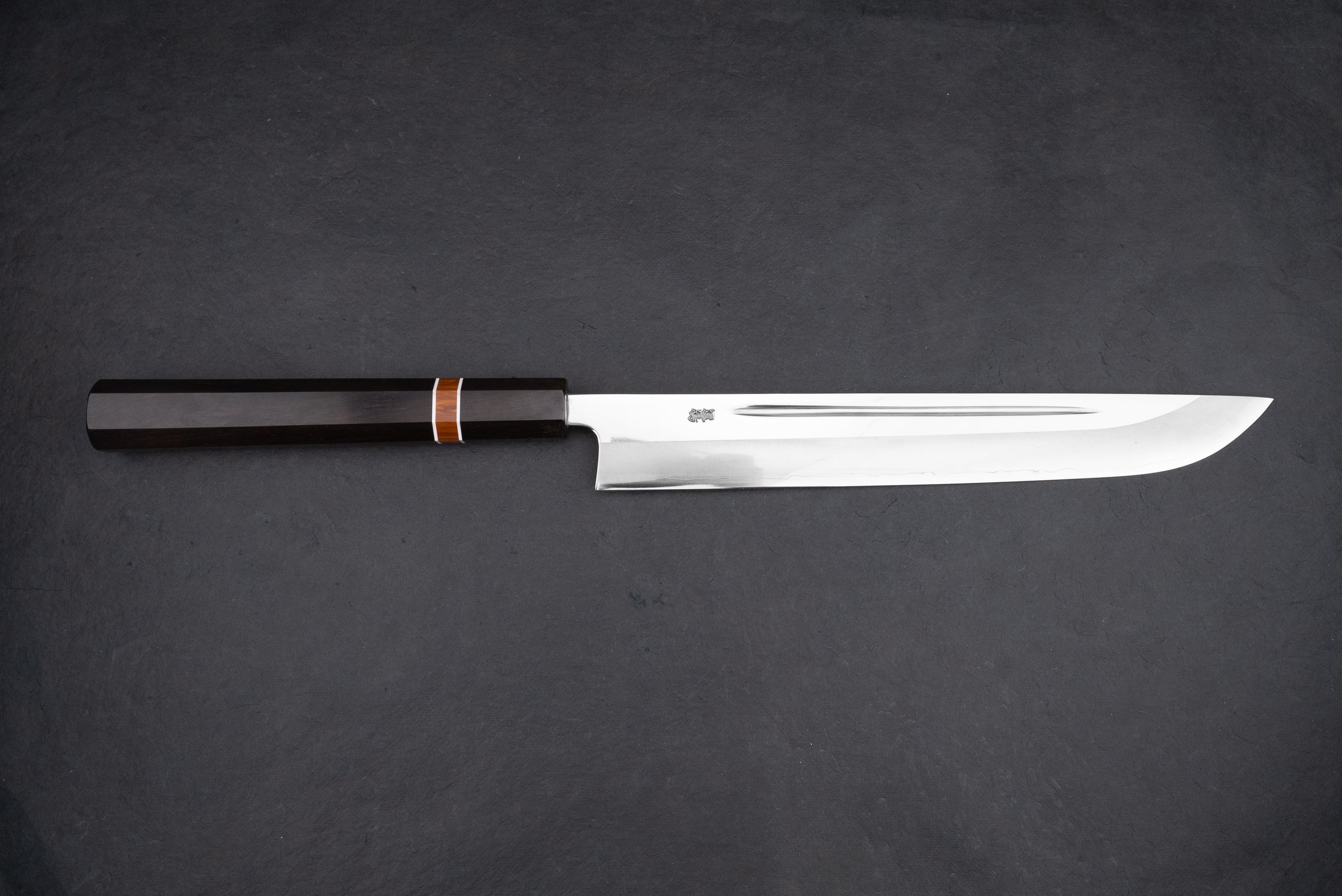 Kurotori Tanzo Ginsan Maguro Bocho, a sleek Japanese slicing knife, features a polished steel blade for precision cuts and a dark octagonal wooden handle, ideal for sashimi preparation.