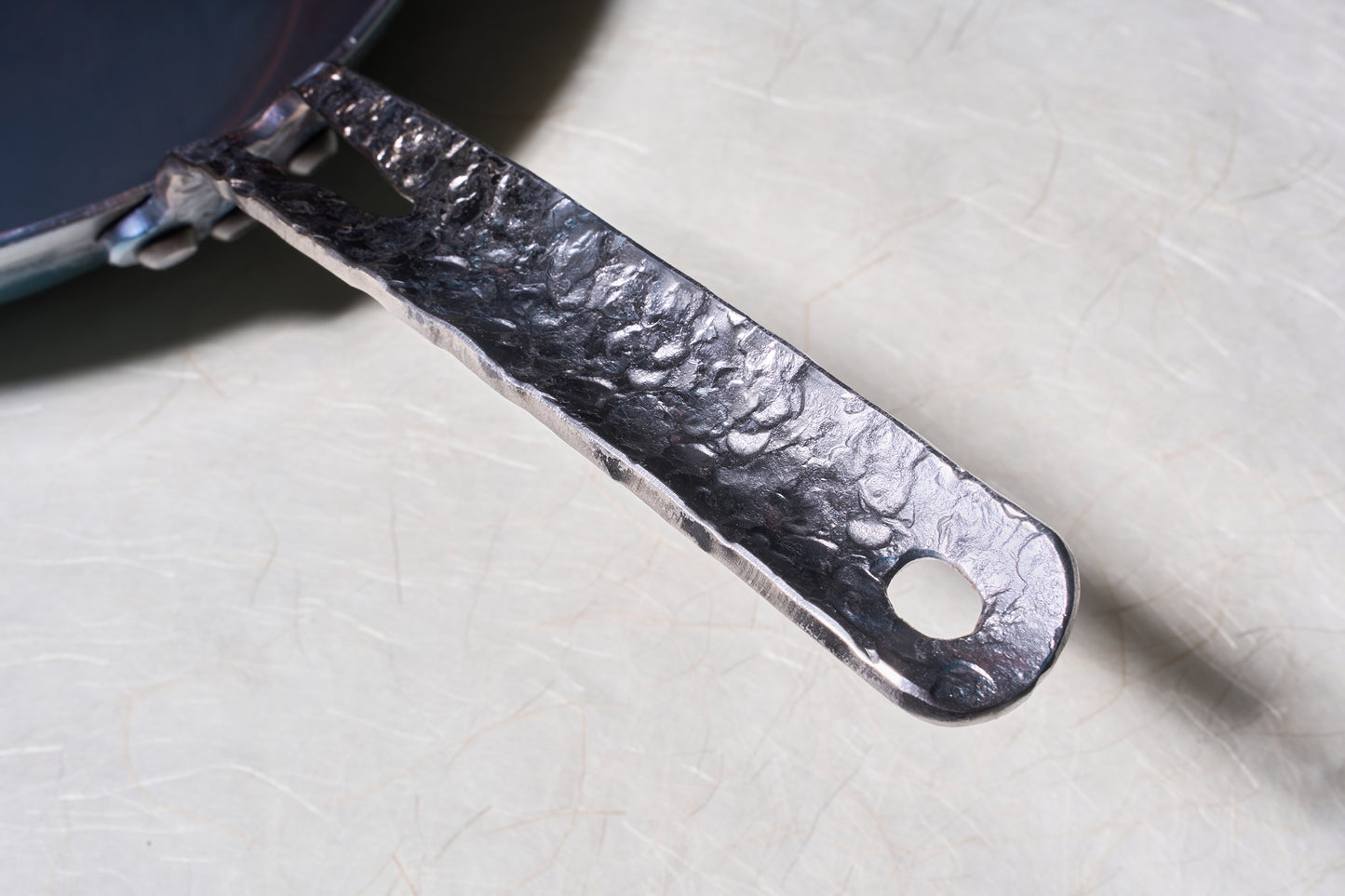 Leechtown Blacksmith Co. Mokwok Carbon Steel Pan Small features a forged, hammered-textured handle, riveted with a hanging loop, perfect for versatile cooking surfaces.