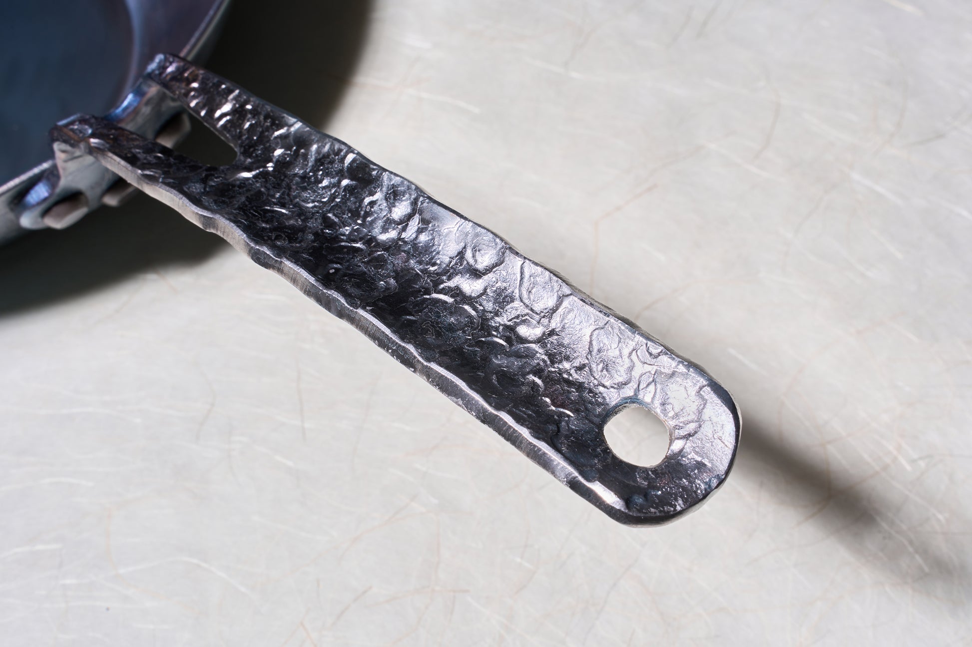 Leechtown Blacksmith Co. Mokwok Carbon Steel Pan Small, featuring a hand-forged, riveted handle with a hanging loop, perfect for versatile cooking surfaces.