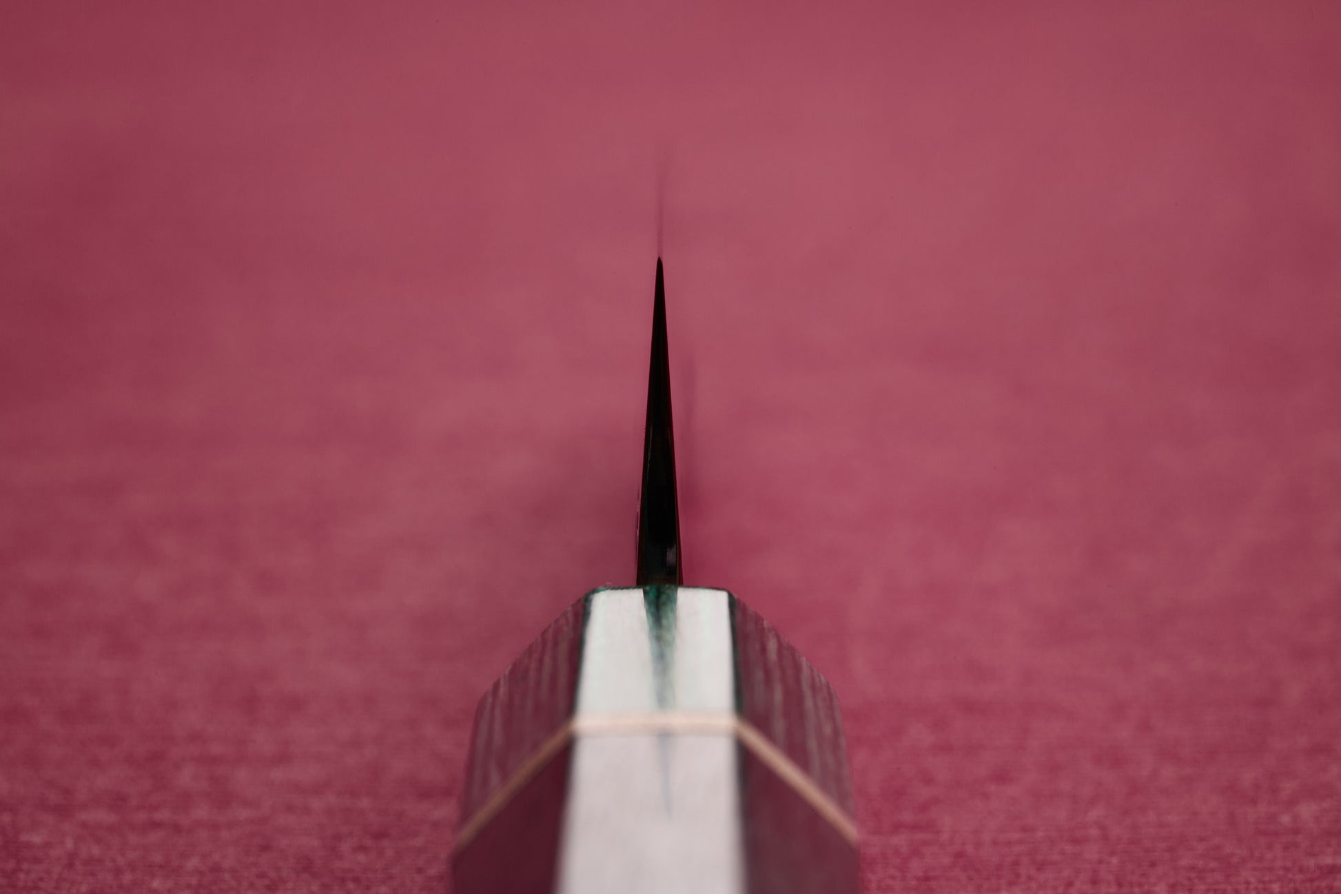 Makoto Kurosaki SPG STRIX Samidorizuki Petty 135mm knife, featuring a razor-sharp blade emerging from an octagonal wooden handle, showcased against a softly blurred red background.