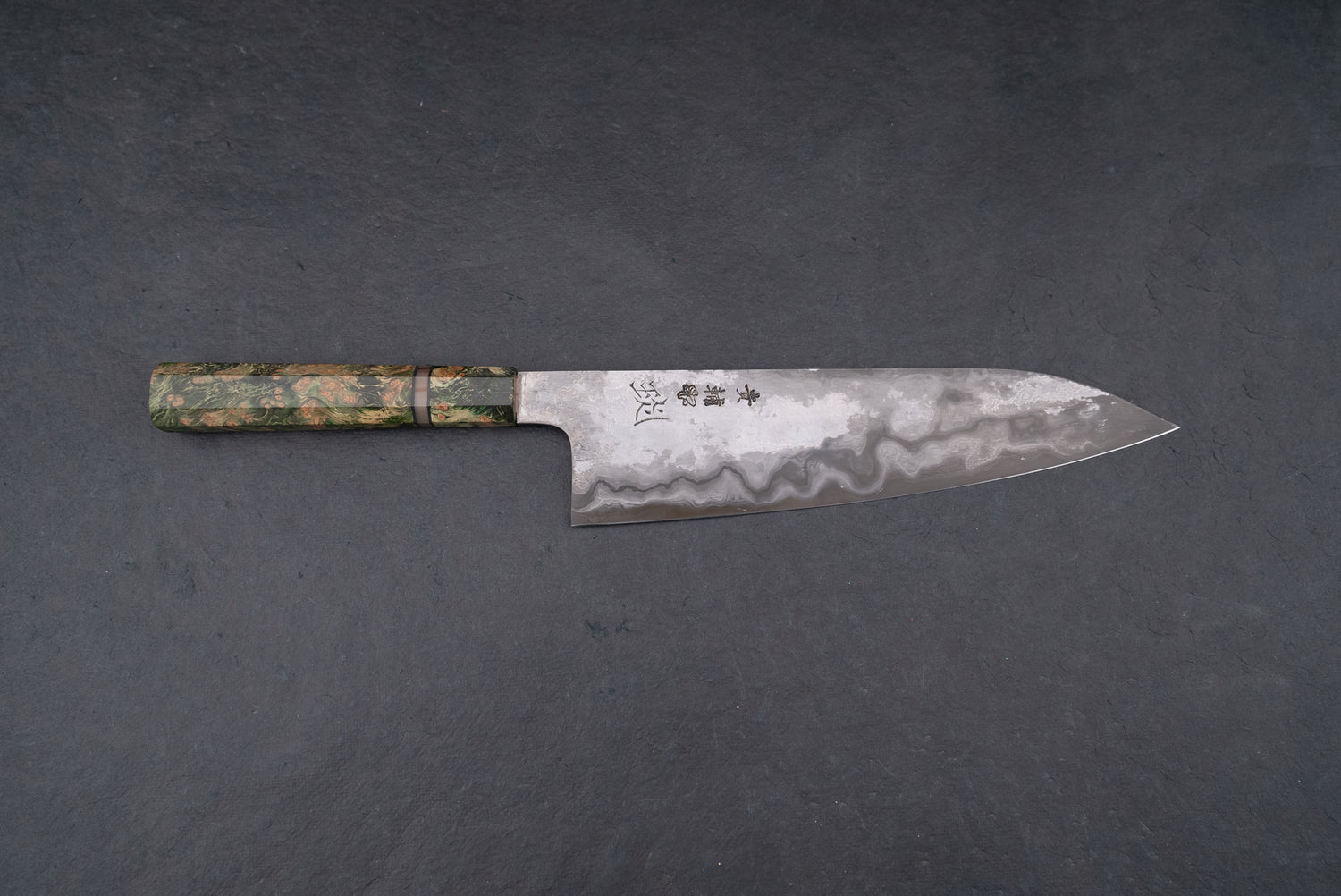 Kisuke Manaka KOKUENN Gyuto 240mm features a water-wave Damascus pattern and kanji on the blade, complemented by a green-toned, octagonal stabilized-wood handle, epitomizing Japanese craftsmanship.