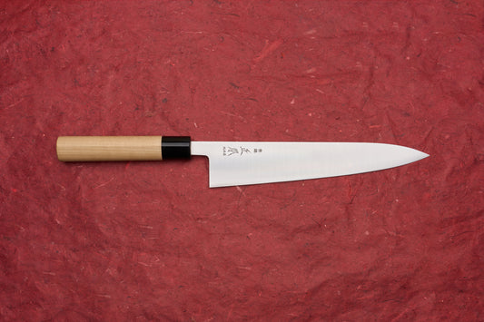 Masamoto KS Hongasumi Gyuto 240mm knife featuring a slender, single-beveled stainless blade with etched kanji, and a smooth wooden handle with a black collar, displayed on a red background.