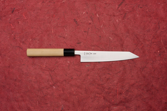 Masamoto KS Hongasumi Kiritsuke Petty 165mm knife with a polished steel blade and Japanese characters, featuring a light wood handle, showcased on a red textured surface.