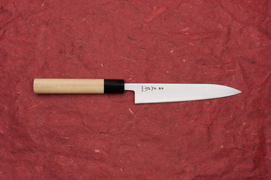 Masamoto KS Hongasumi Petty 165mm, a meticulously crafted Japanese kitchen knife with a polished steel blade and light wooden handle, displayed on a red surface, exemplifying Masamoto's renowned precision and thinness.