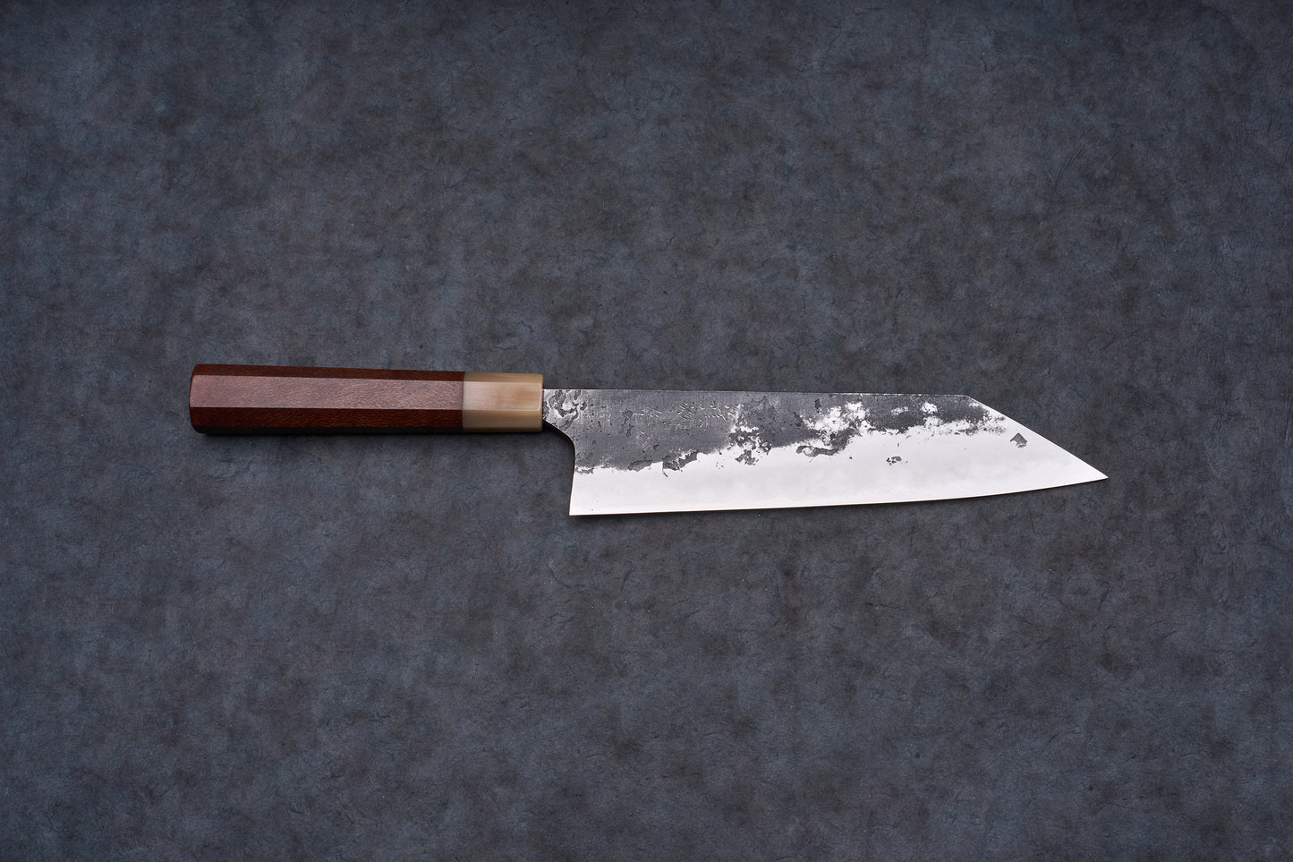 Mazaki Aogami Super Honsanmai Kurouchi Nashiji Kiritsuke Gyuto 210mm, a Japanese-style knife with a broad steel blade and octagonal wooden handle, displayed on a dark surface.