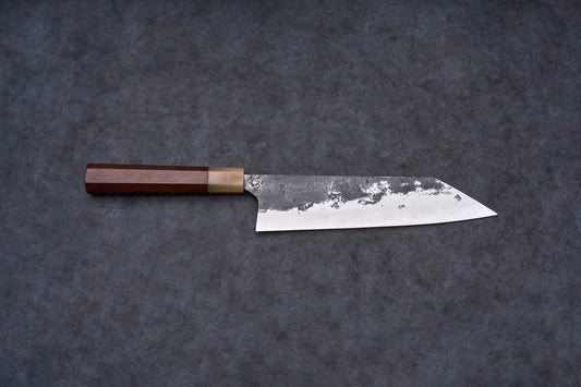 Mazaki Aogami Super Honsanmai Kurouchi Nashiji Kiritsuke Gyuto 210mm, a Japanese-style knife with a broad steel blade and octagonal wooden handle, displayed on a dark surface.