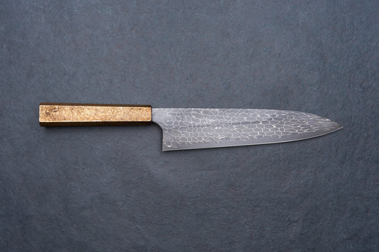 Mazaki Aoichi Beads Black Damascus Gyuto 240mm knife on slate surface, featuring a patterned steel blade and a straight, rectangular wooden handle.