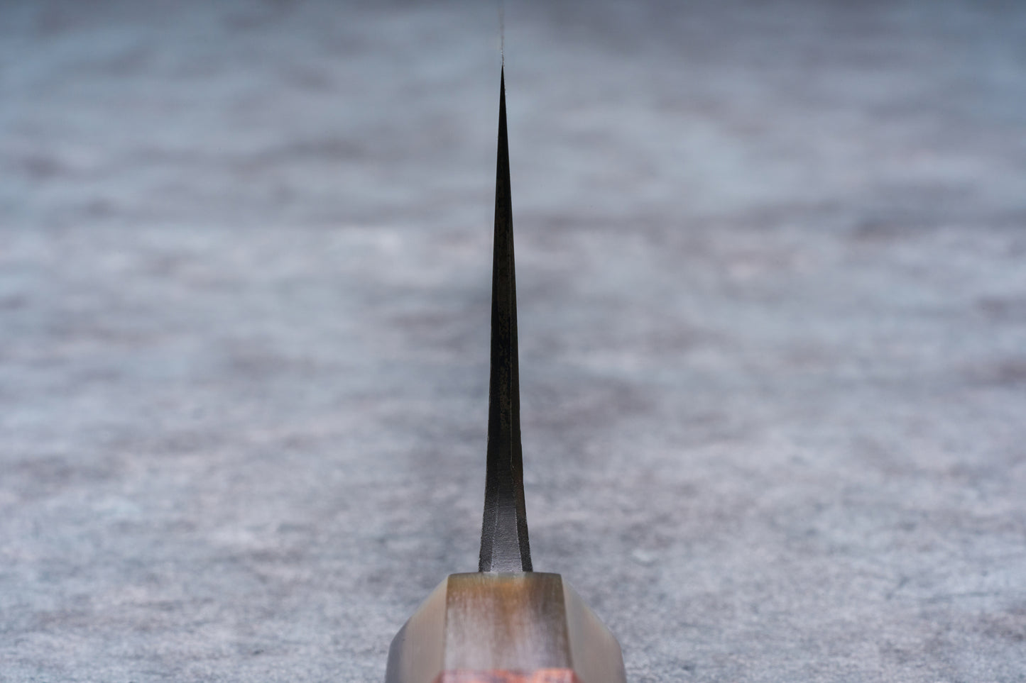 Mazaki Aoichi Honsanmai Kurouchi Nashiji Kiritsuke Gyuto 240mm knife blade edge-on, emerging from a wooden handle, crafted by young blacksmith Mazaki-san.