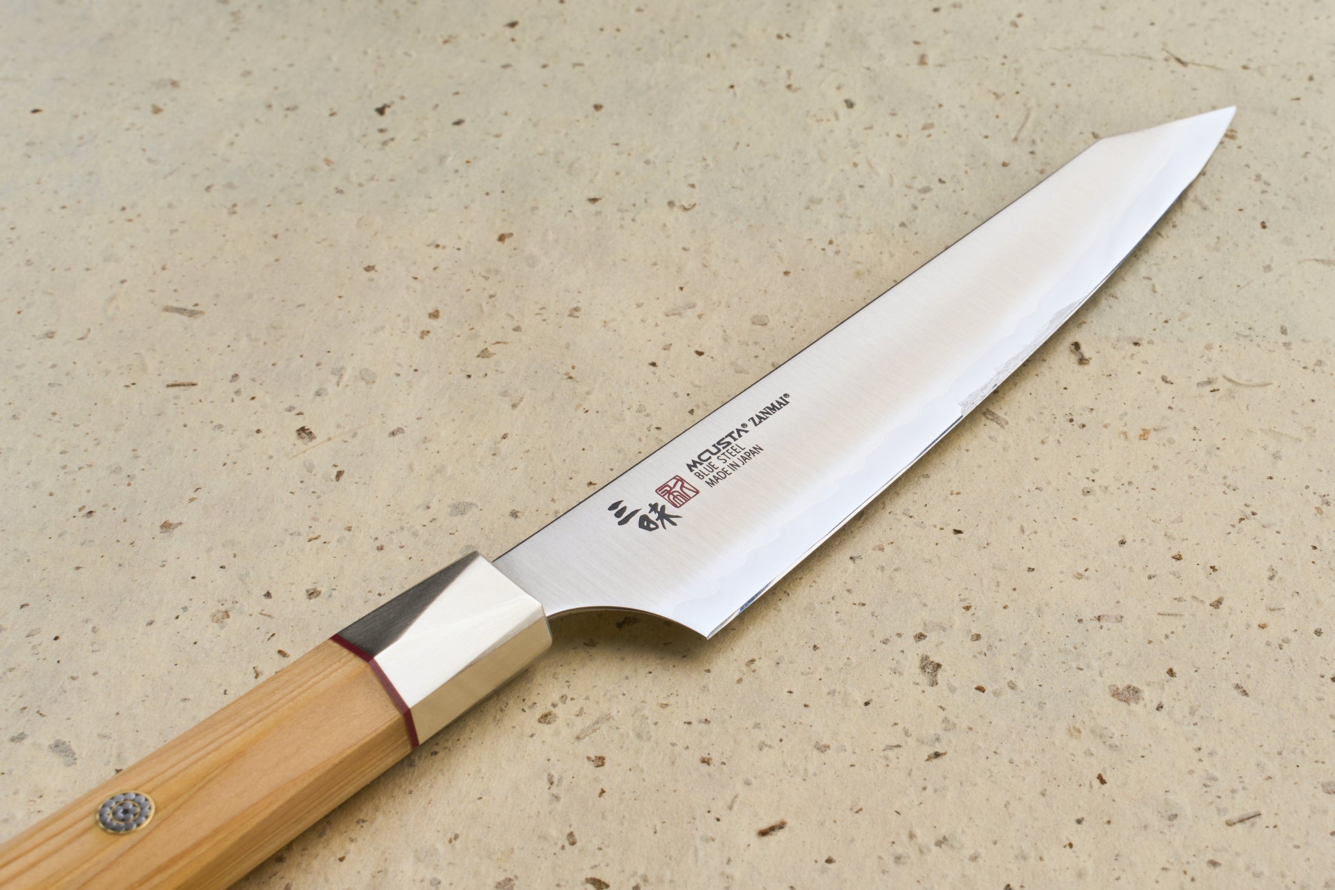 Mcusta Zanmai Beyond Kiritsuke Petty 150mm, a handcrafted Japanese kitchen knife, features a yanagiba blade with Japanese inscriptions, polished bolster, and octagonal wooden handle. Ideal for precision slicing and smaller kitchen tasks.