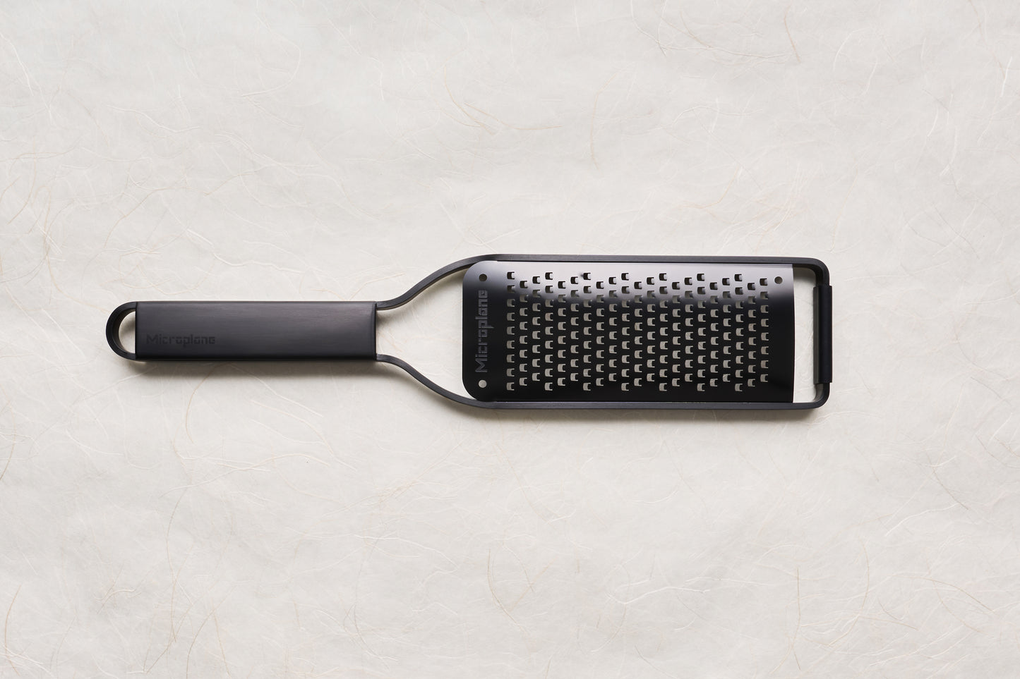 Microplane Black Sheep Series Grater with a sleek black handle and stainless steel blade, designed for zesting citrus and grating hard cheeses, embodying sharpness and precision ideal for culinary enthusiasts.