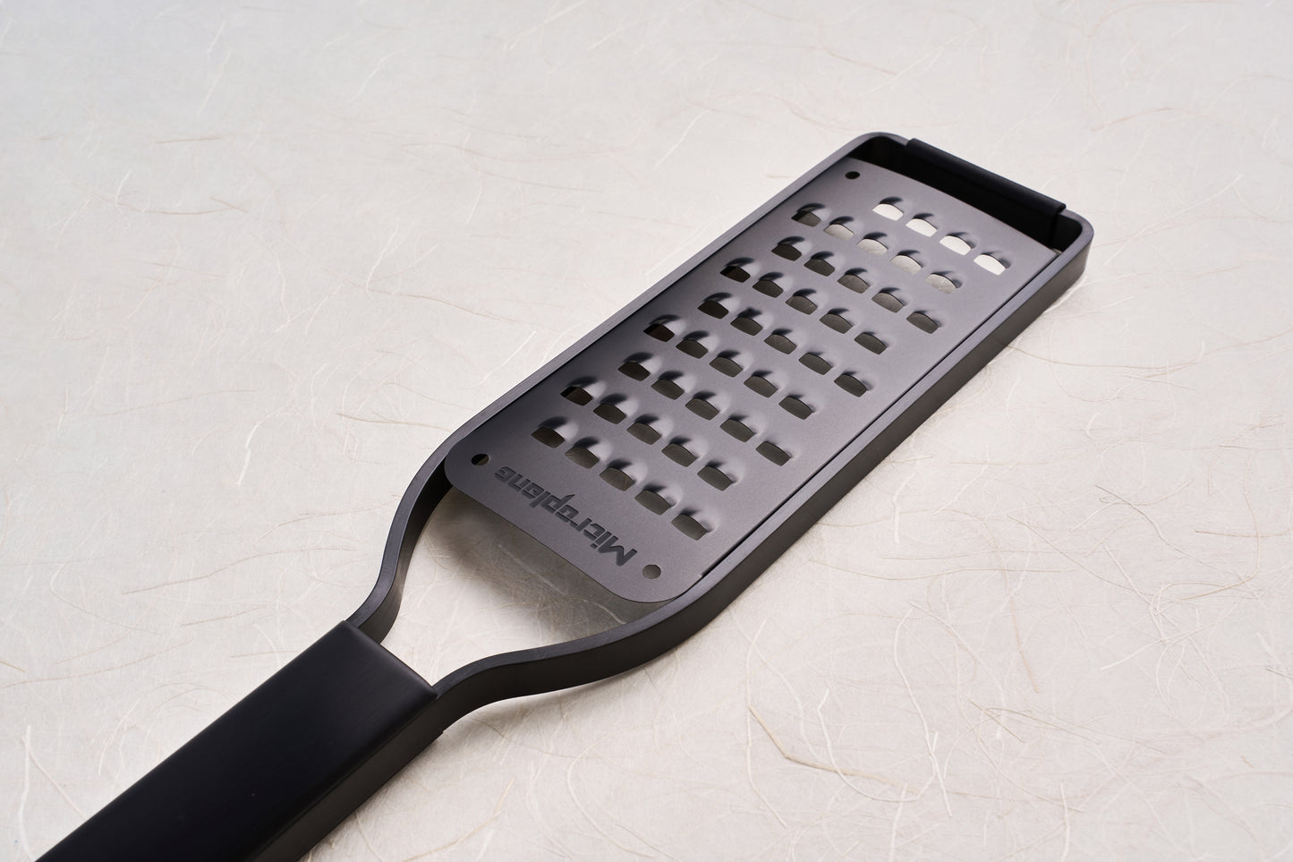 Microplane Black Sheep Series Grater, featuring a sleek, black handle and razor-sharp perforated surface, ideal for zesting citrus and grating hard cheeses, garlic, and spices, embodying superior kitchen tool craftsmanship.