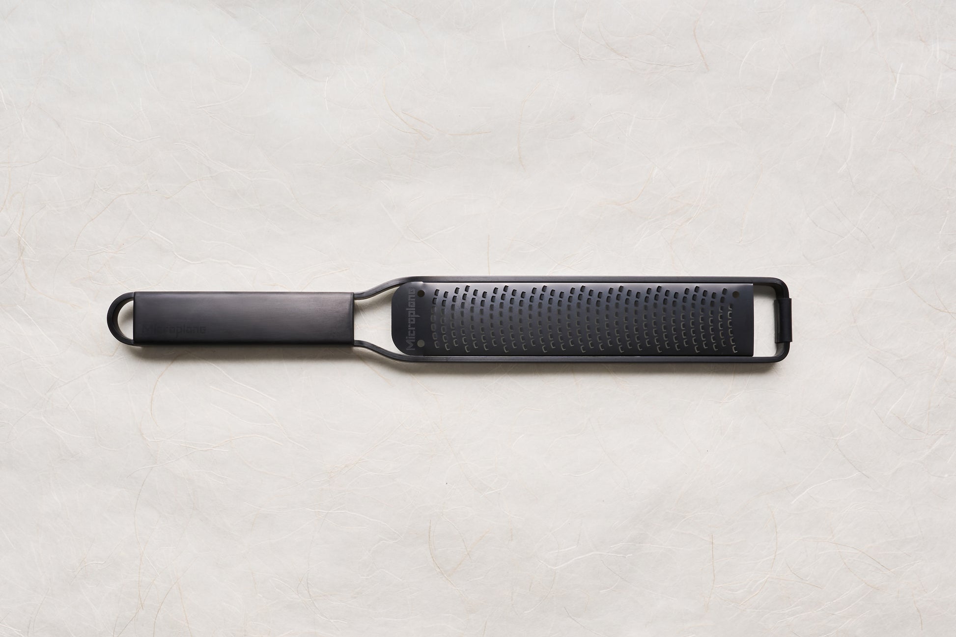 Microplane Black Sheep Series Grater with sharp stainless-steel blade and ergonomic handle, designed for precise zesting and grating of citrus, cheese, and spices, embodying superior culinary craftsmanship.