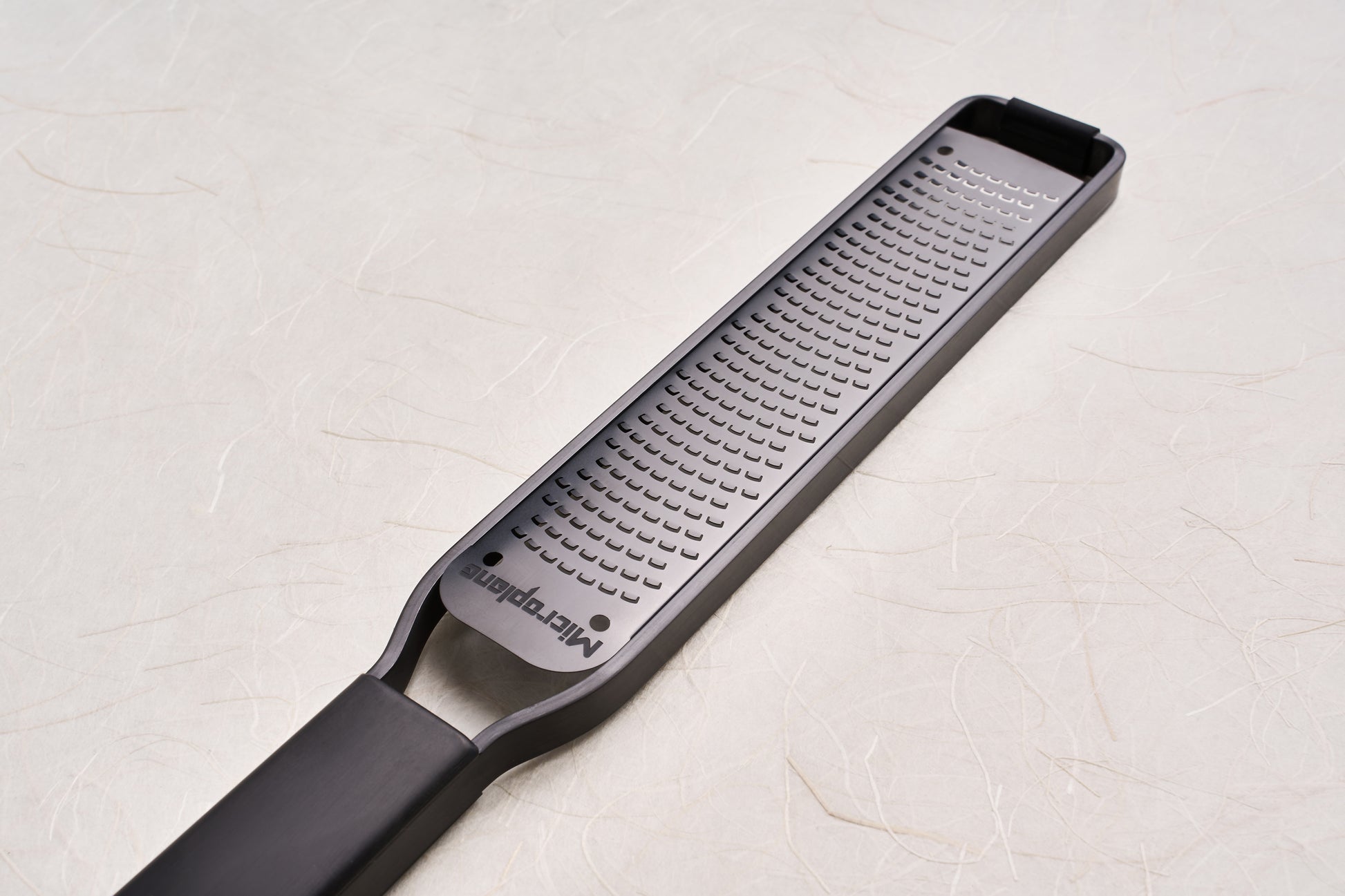Microplane Black Sheep Series Grater, featuring a long, narrow stainless-steel rasp with patented sharp cutting teeth and a sleek black handle, ideal for zesting citrus and grating hard cheeses or spices.