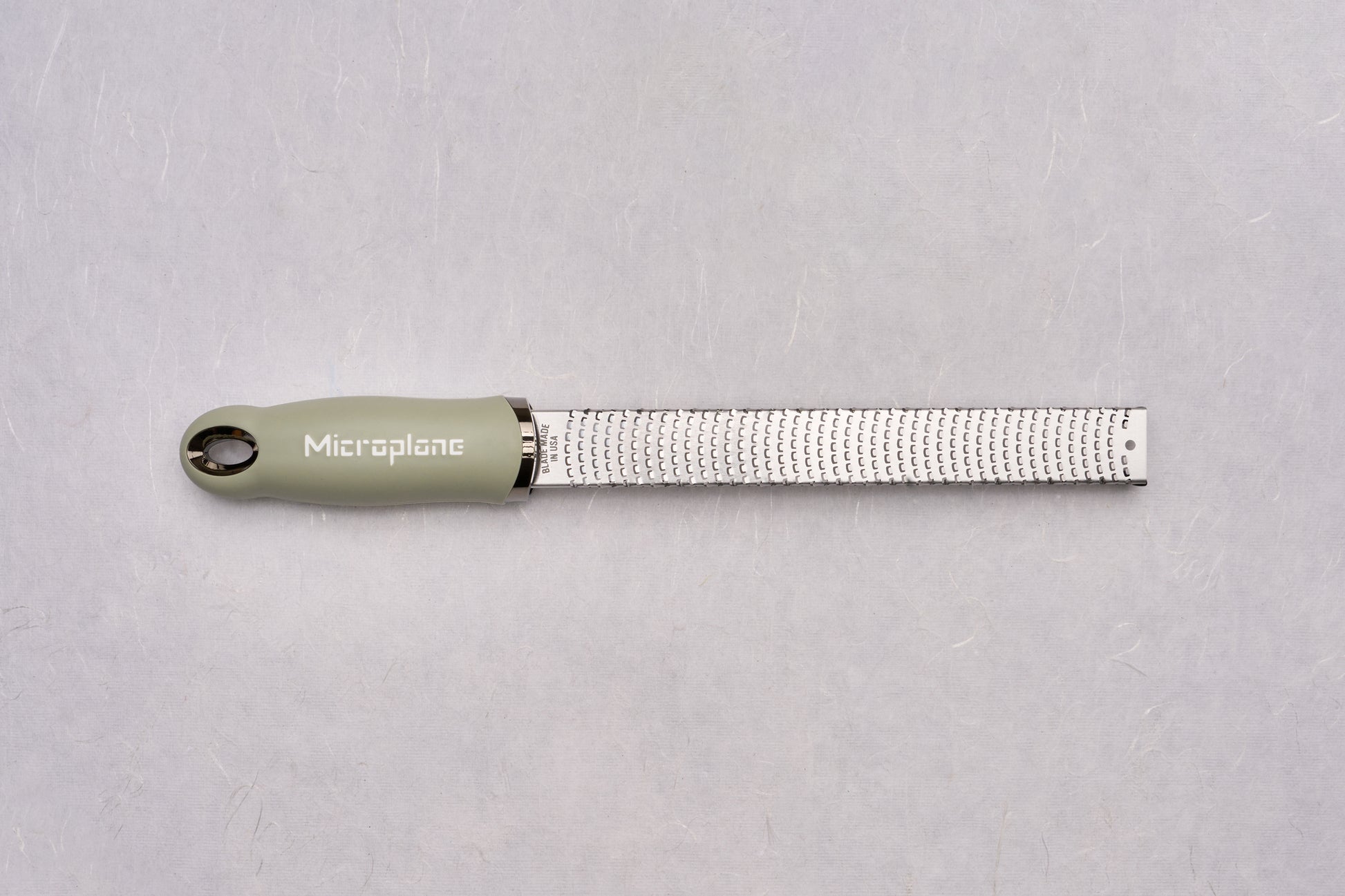 Microplane Premium Classic Zester, featuring a sleek stainless-steel blade and an ergonomic olive-green handle, ideal for zesting citrus or grating hard cheeses, a must-have tool for culinary precision.