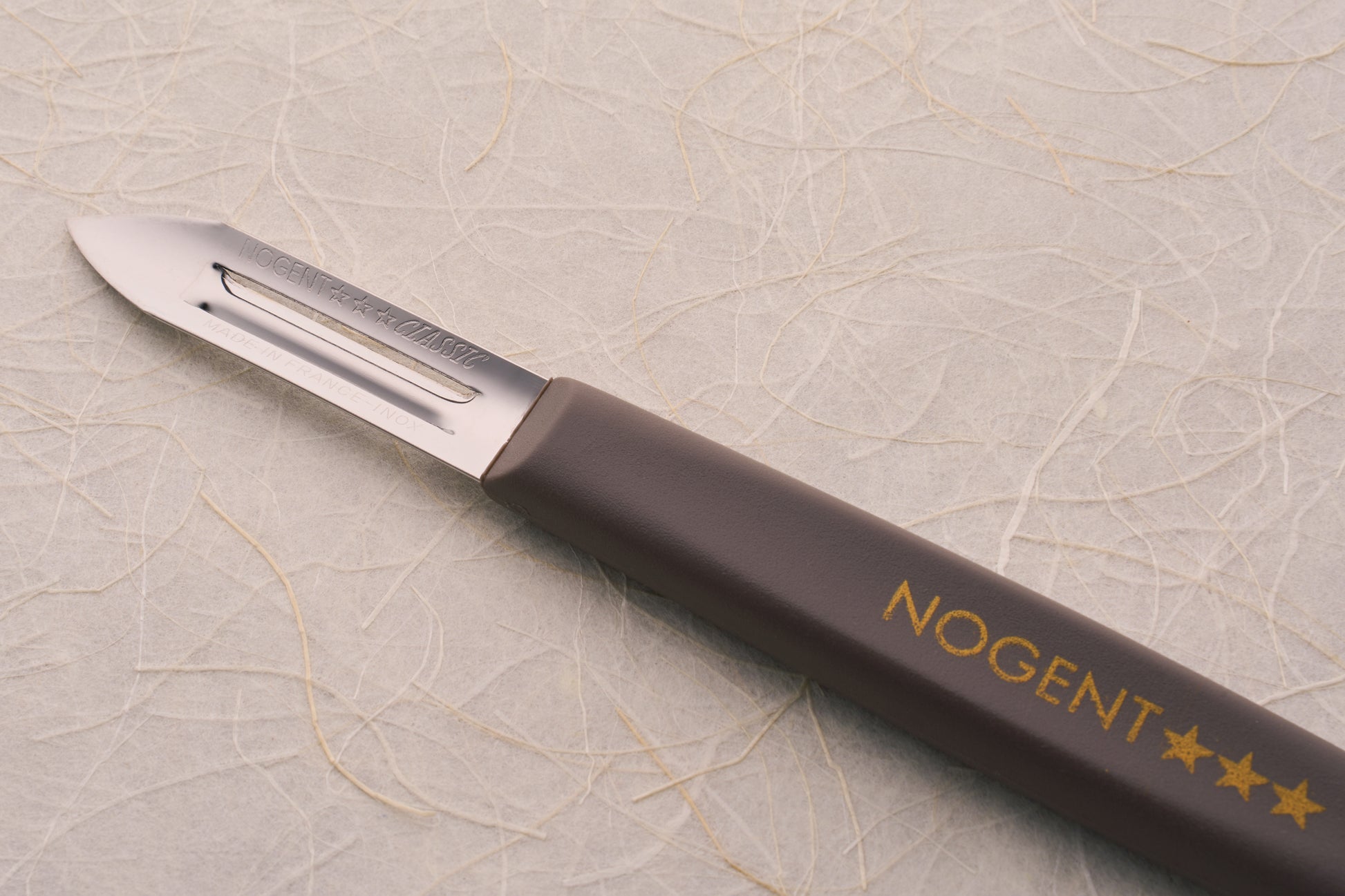 Nogent Double Edge Peeler with a stainless-steel blade and brown handle, designed for dual directional peeling, showcasing craftsmanship and durability.