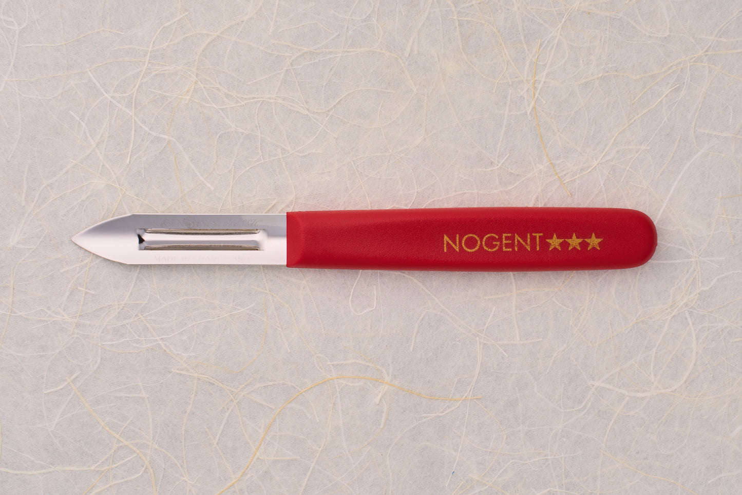 Nogent Double Edge Peeler with red handle and stainless steel blade, ideal for precise, dual-directional peeling. Lightweight, durable design favored by culinary enthusiasts.