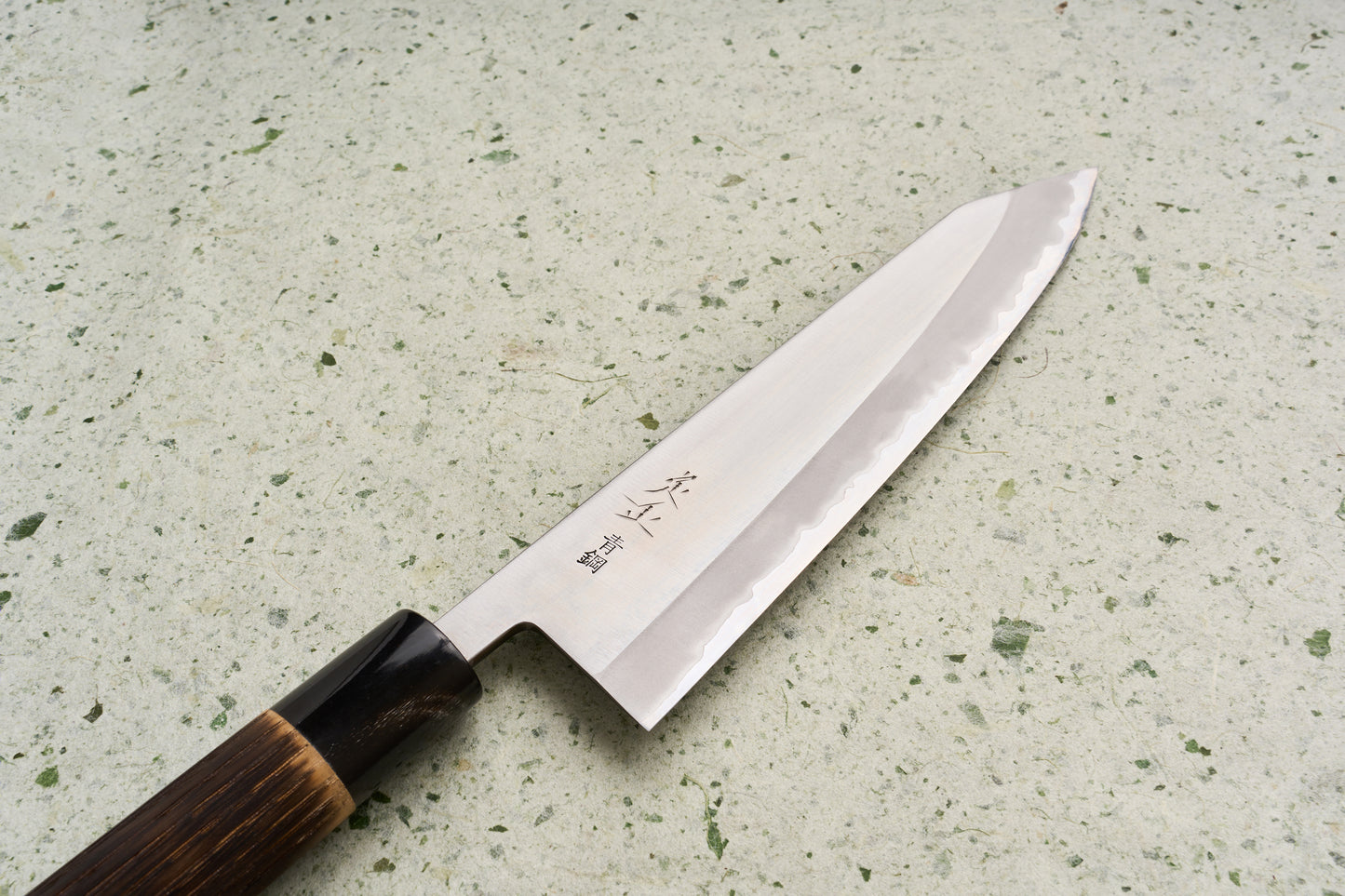 Sadamasa Aogami Stainless Migaki Kiritsuke Gyuto 210mm knife showcases a polished steel blade with hamon, a wooden handle with dark ferrule, and engraved Japanese characters, ideal for versatile kitchen use.