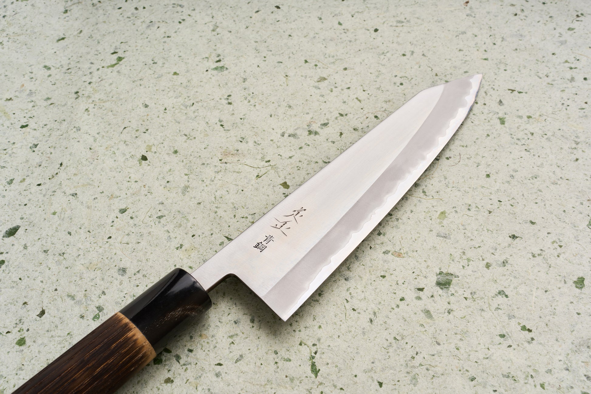 Sadamasa Aogami Stainless Migaki Kiritsuke Gyuto 210mm knife showcases a polished steel blade with hamon, a wooden handle with dark ferrule, and engraved Japanese characters, ideal for versatile kitchen use.