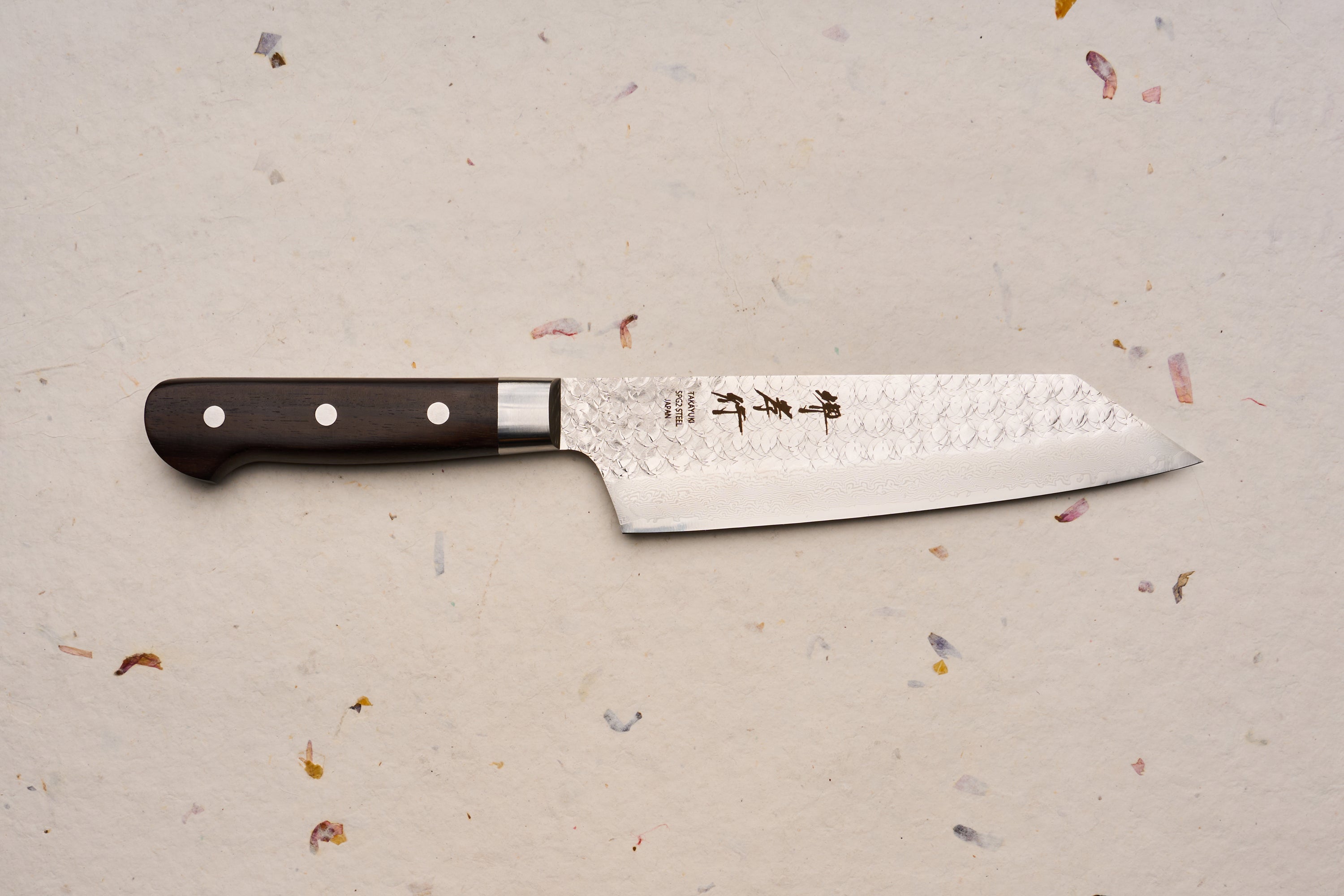 Sakai Takayuki SG2 Tsuchime Damascus Western Kengata Gyuto 190mm features a hammered, Damascus-patterned steel blade with Japanese characters and a dark wooden handle, embodying expert craftsmanship ideal for culinary enthusiasts.